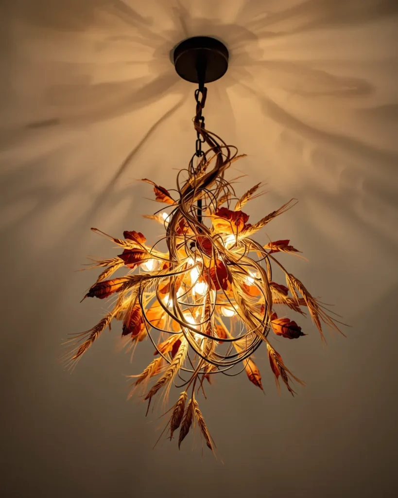 Close-up of a rustic pendant light fixture wrapped with delicate dried wheat stems and autumnal foliage for warm Thanksgiving ambiance