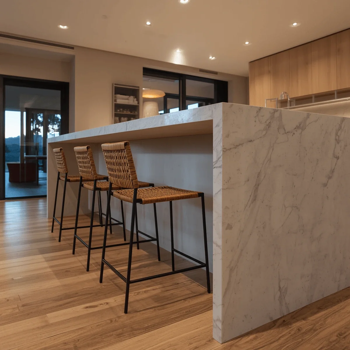Marble waterfall kitchen island with woven rattan counter stools for seating